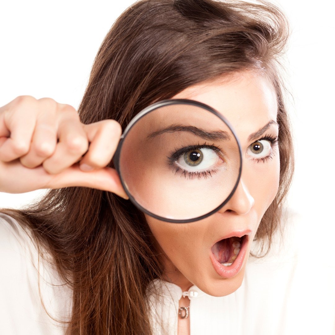 Woman with a magnifying glass to her eye to signify being found through BigCommerce SEO