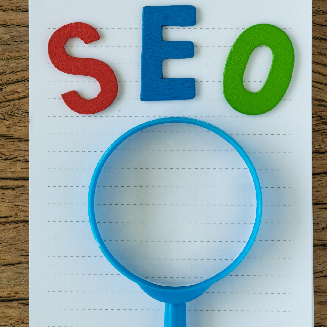 BigCommerce SEo symbolized here by colorful SEO letters on a notepad with a blue magnifying glass